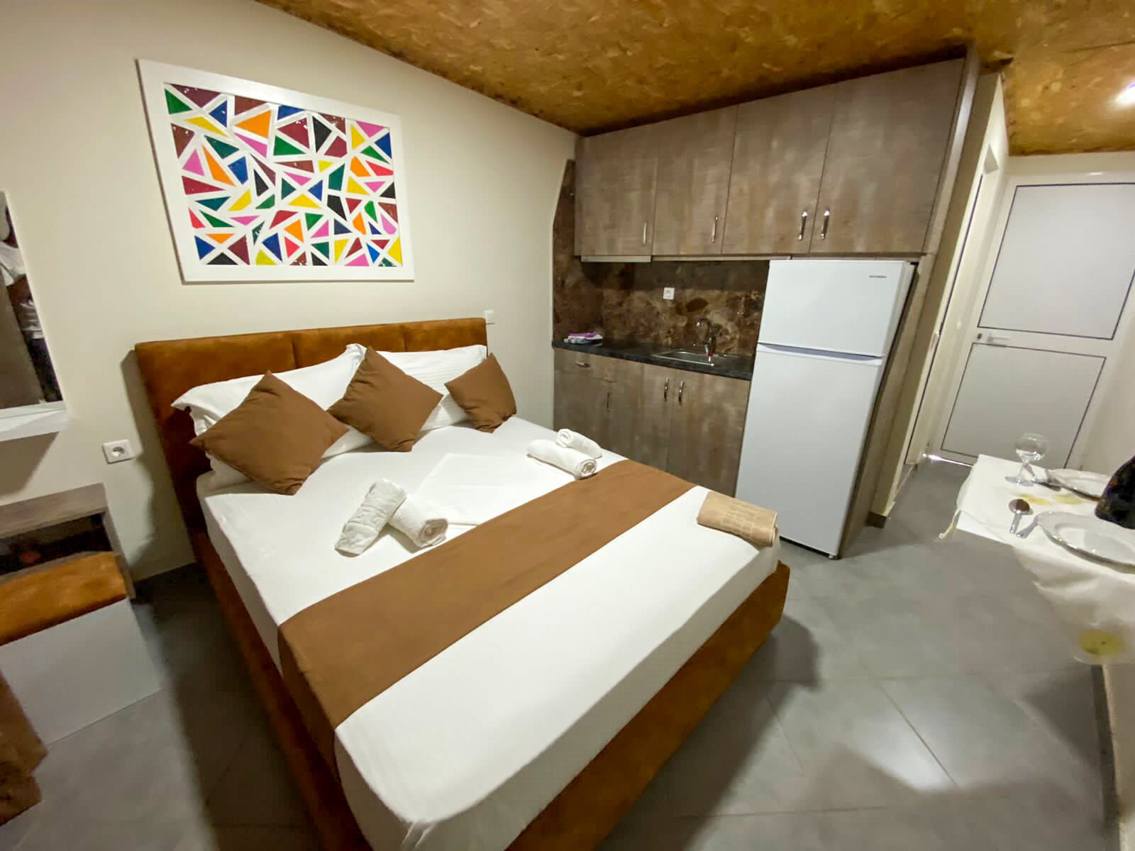 A hotel room with a bed, a bathroom, and a kitchenette.