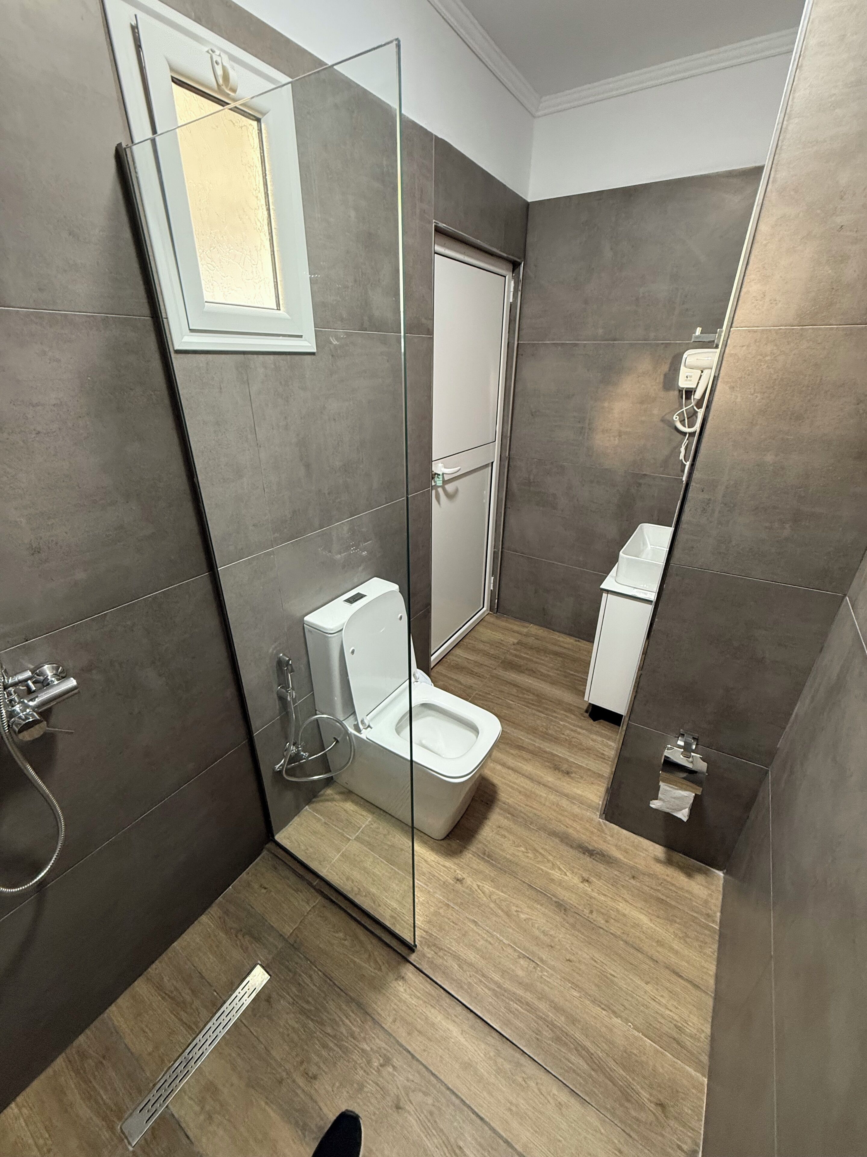 A modern bathroom with a glass-enclosed shower, a toilet, and a sink.