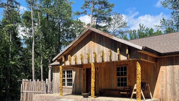 A wooden building with a stone foundation, large windows, and a porch with a stone bench. - Kings Court (Dalton)