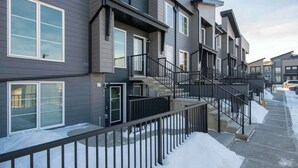 A multi-story residential building with balconies, a staircase, and a snow-covered ground. - King Bed Mtn Escape Free Parking 1hr to Banff (Calgary)