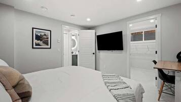 Une chambre à coucher avec un lit, un téléviseur fixé au mur et un bureau avec une chaise.