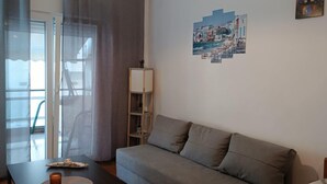 Ein Wohnzimmer mit grauem Sofa, einem schwarzen Couchtisch, einer Lampe, einem Gemälde und einem Ventilator.