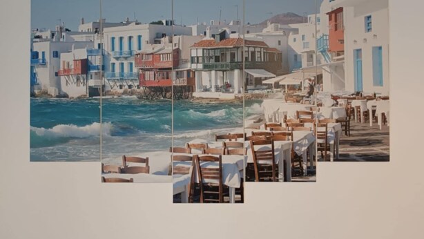 Eine Küstenstadt mit weißen Gebäuden, blauen Türen und einem Restaurant am Strand mit Außenbereich.