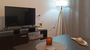Ein modernes Wohnzimmer mit einem dunklen Holztisch, einem Flachbildfernseher und einer Stehlampe.