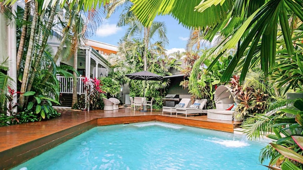 A swimming pool with lounge chairs and umbrellas, surrounded by tropical plants. - Mantra on the Inlet Port Douglas (Port Douglas)