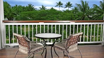 A wooden deck with a white railing, two wicker chairs, and a round table.