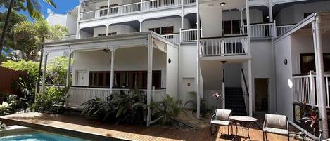 A two-story building with balconies, a pool, and outdoor seating.