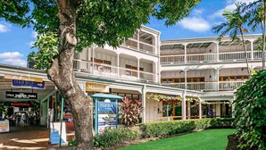 A multi-story building with a central courtyard, surrounded by various shops and a signboard for a massage service. - Mantra on the Inlet Port Douglas (Port Douglas)