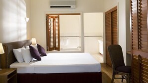 A hotel room with a bed, a chair, a ceiling fan, an air conditioning unit, and a view through a door to an outdoor balcony. - Mantra on the Inlet Port Douglas (Port Douglas)