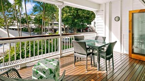 A balcony with a ceiling fan, a glass door, and a view of palm trees and buildings. - Mantra on the Inlet Port Douglas (Port Douglas)