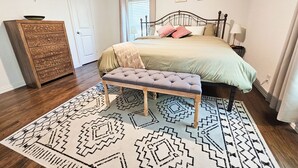 A bedroom with a bed, a bench, a dresser, and a patterned rug. - Cornerstone Retreat in Arlington (Arlington)
