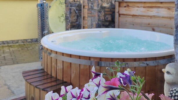 A wooden hot tub with a stone wall and a wooden fence in the background. - Awesome home in Zuta Lokva with WiFi (Zuta Lokva)