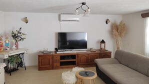 A living room with a flat-screen TV, wooden entertainment unit, sofa, and a small round table with a remote control. - Awesome home in Zuta Lokva with WiFi (Zuta Lokva)