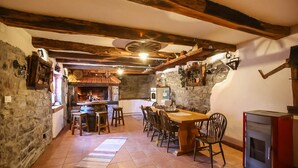 A rustic dining area with a stone wall, wooden beams, a fireplace, and a tiled floor. - Awesome home in Zuta Lokva with WiFi (Zuta Lokva)