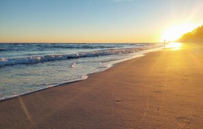 En strand med vågor och en solnedgång.