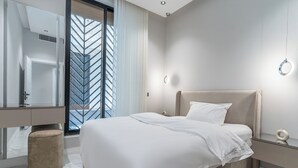A modern hotel room with a large bed, a vanity with a mirror, and a view of a building through a window with sheer curtains. - Fancy hosting (Riyadh)