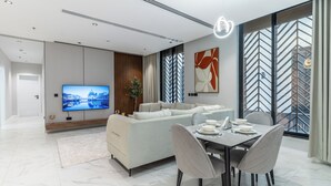 A modern living room with a sofa, dining table, and TV. - Fancy hosting (Riyadh)