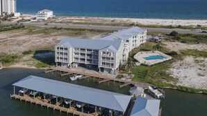 Un hôtel situé au bord de l’eau, composé de plusieurs bâtiments, avec un quai où sont amarrés des bateaux et une piscine.