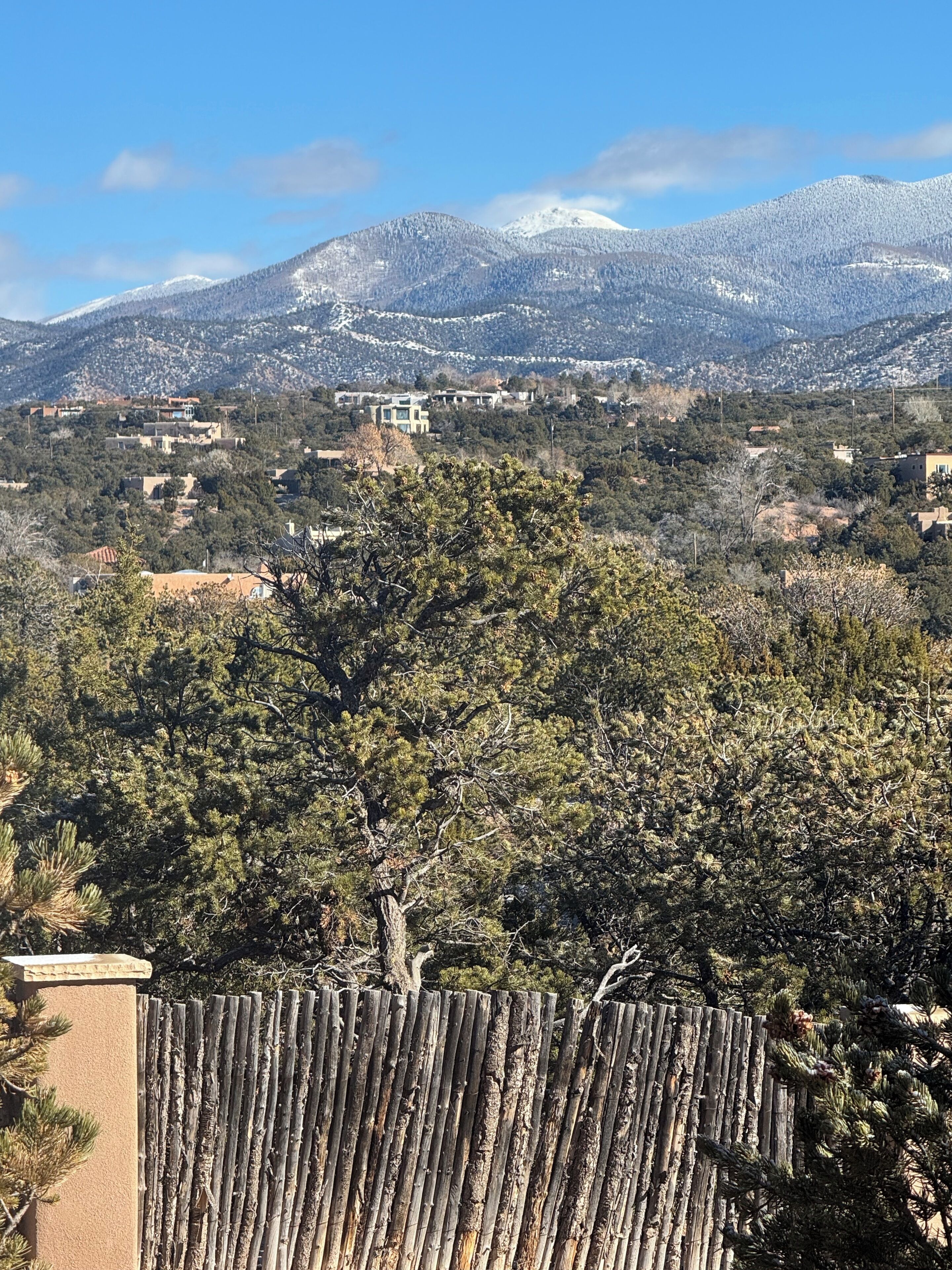 A mountainous landscape with residential buildings and a wooden fence in the foreground.