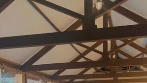 Une piscine intérieure avec des poutres en bois et des rideaux à motifs.