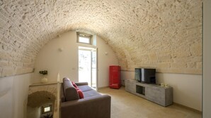 Una sala de estar acogedora con techo de piedra, un sofá, un mueble rojo y un televisor.