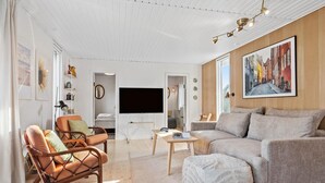 A modern living room with a sofa, armchairs, a coffee table, and a TV. - 3 bedroom awesome home in Odder (Odder)