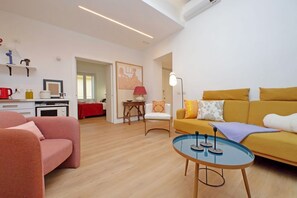 Una sala de estar moderna con un sofá, una mesa de centro y un comedor con mantel rojo.