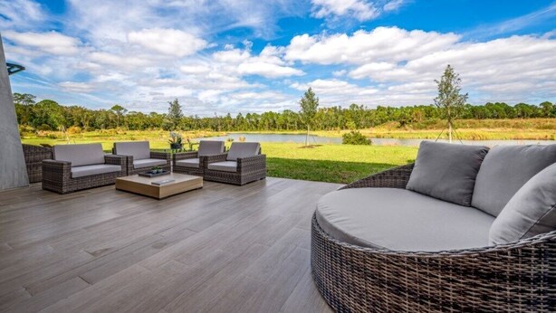 An outdoor seating area with wicker furniture and a view of a lake and forest. - 3 Bedrooms Stylish Townhouse Near Disney (Kissimmee)