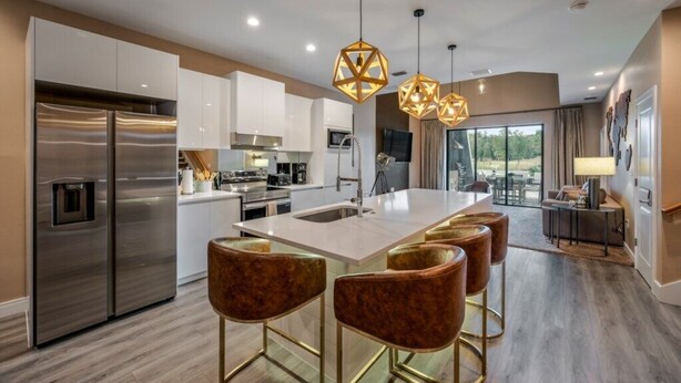 A modern kitchen with stainless steel appliances, a central island with bar stools, and pendant lighting. - Modern Family Villa Close to Disney & Dining (Kissimmee)