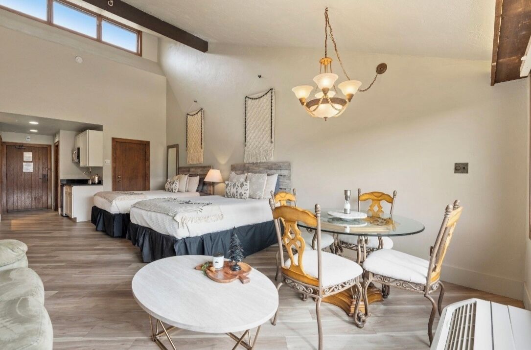 Ein geräumiges Schlafzimmer mit einem großen Bett, einem Esstisch mit Stühlen und einer Chandelier.