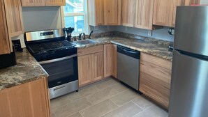 Eine moderne Küche mit Holzausstattung, Edelstahlgeräten und einer Arbeitsplatte aus Granit.