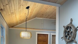 Ein Essbereich mit Holztisch und Stühlen, einer Pendelleuchte und einer Schiffsausrüstung als Wanddekoration.