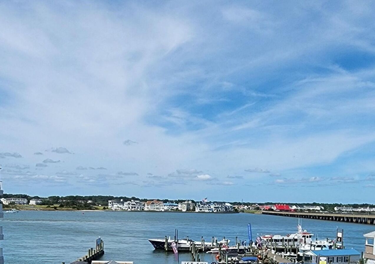 Un port de plaisance avec des bateaux amarrés, une jetée qui s’avance dans l’eau et une ville en arrière-plan.