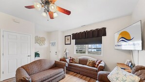 A living room with a ceiling fan, two sofas, a TV, and a window with a view.