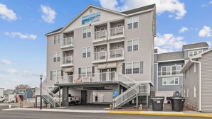 Un hotel de varios pisos con balcones, entrada cubierta y zona de estacionamiento.