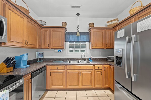 A kitchen with wooden cabinets, a stainless steel refrigerator, a sink, and a coffee maker.