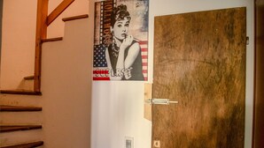 Una escalera de madera que lleva a una habitación con una puerta de madera y un cartel en la pared.