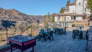 Un patio con mobiliario exterior y mesa de fútbol de mesa, con vistas a un paisaje montañoso.