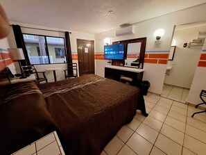 A hotel room with a bed, desk, chair, TV, and a bathroom with a mirror and sink. - Motel Jabaloyas (Tijuana)