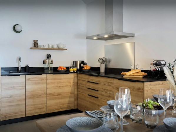 Una cocina moderna con armarios de madera, una encimera negra y un comedor con una mesa preparada para dos.