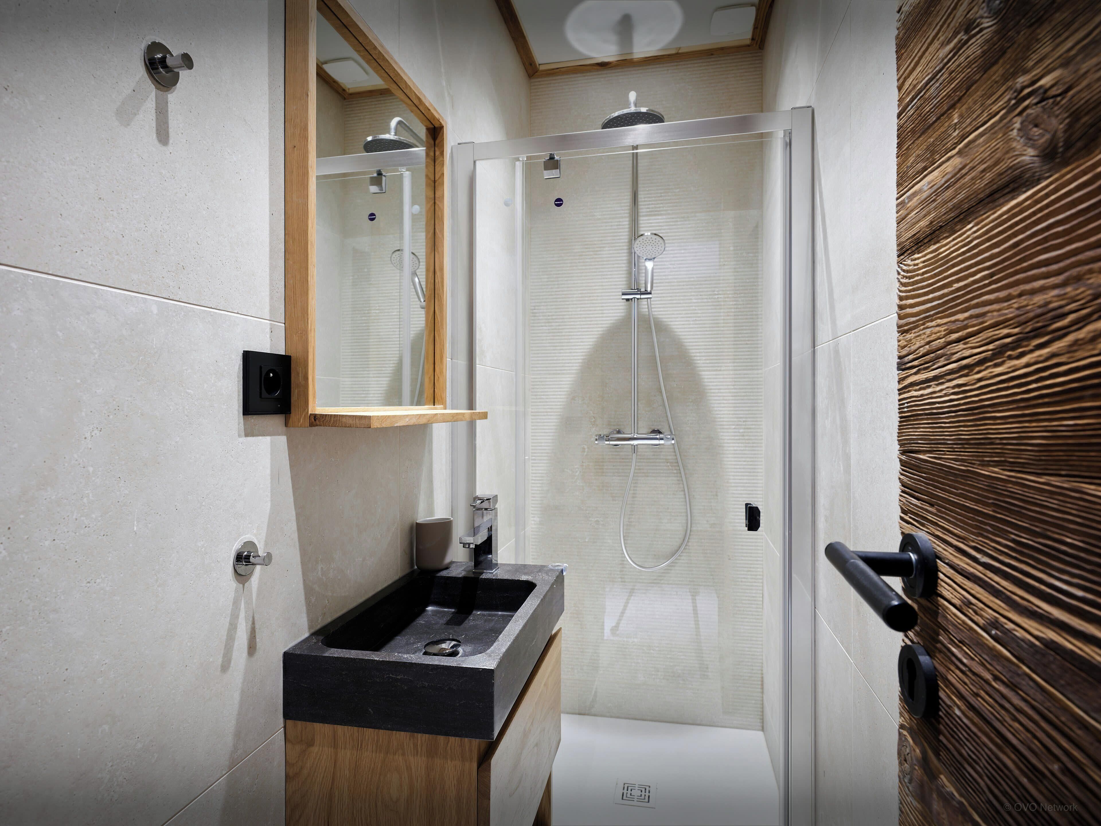Un baño moderno con ducha, lavamanos y espejo.