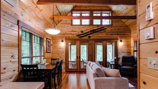 A wooden cabin interior with a dining area, sofa, and a fireplace. -  Cozy, charming two bedroom McKenzie Bridge River front cabin for 2 Guests, (McKenzie Bridge)