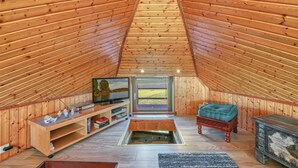 A cozy attic room with wooden walls, a television, a sofa, and a fireplace. - 1 bedroom lovely home in Neukalen (Neukalen)