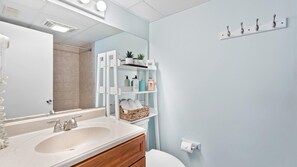 Bathroom features a large mirror, sink, toilet, and shelves for toiletries.