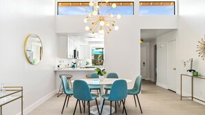 A modern dining area with a round table, teal chairs, and a central plant.