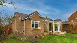 A brick house with a conservatory, a visible satellite dish, and a small garden area.