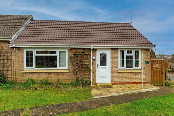 A single-story brick house with a tiled roof, a front door, and a small porch area.