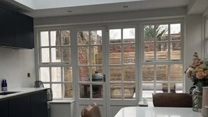 Una cocina moderna con una gran mesa de comedor, armarios oscuros y vistas al exterior a través de amplios ventanales.