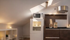 A modern kitchen with a built-in microwave, a stainless steel range hood, and a dark brown cabinet. - Tico en Madrid - Ideal Para Parejas (Madrid)
