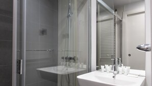 A modern bathroom with a glass-enclosed shower, a white sink, and toiletries. - Tico en Madrid - Ideal Para Parejas (Madrid)